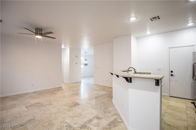 kitchen featuring a kitchen breakfast bar, sink, ceiling fan, and an island with sink