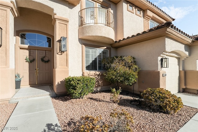 view of exterior entry with a garage and a balcony