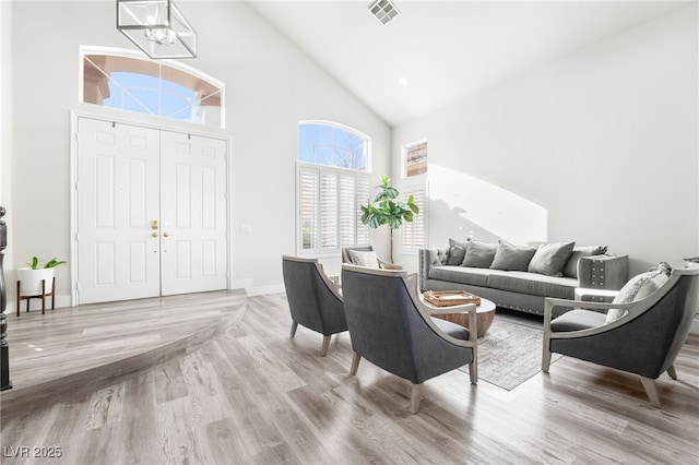 living room featuring a chandelier, a high ceiling, and light hardwood / wood-style floors