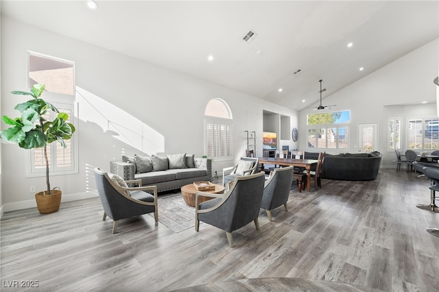 living room with ceiling fan, high vaulted ceiling, and light wood-type flooring