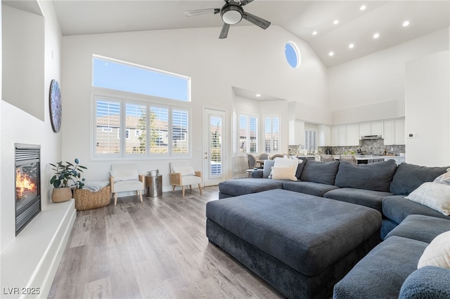 living room featuring light wood-type flooring, high vaulted ceiling, and ceiling fan