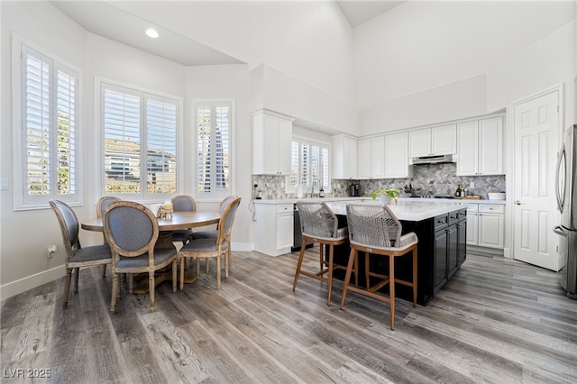 kitchen with white cabinetry, stainless steel fridge, plenty of natural light, light hardwood / wood-style floors, and a kitchen island