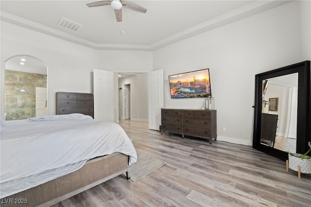 bedroom with a high ceiling, light wood-type flooring, ensuite bathroom, and ceiling fan