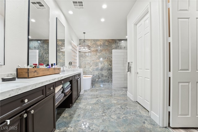 bathroom with vanity, a tub to relax in, and tile walls