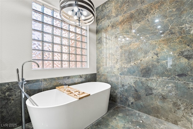 bathroom featuring a bath and tile walls