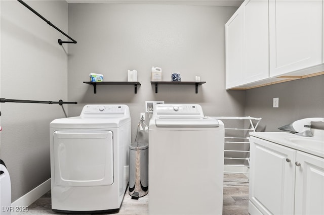 clothes washing area with cabinets, light hardwood / wood-style flooring, and washing machine and clothes dryer