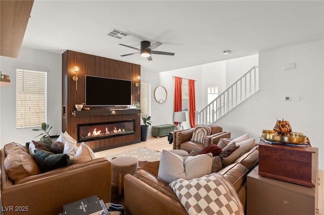 living room with ceiling fan, a fireplace, and light wood-type flooring