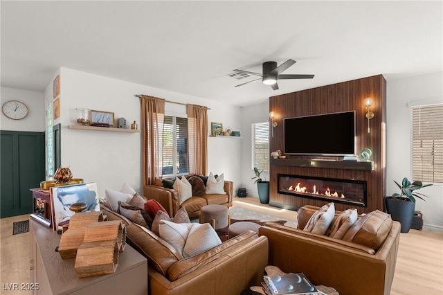 living room with a fireplace, light hardwood / wood-style flooring, and ceiling fan