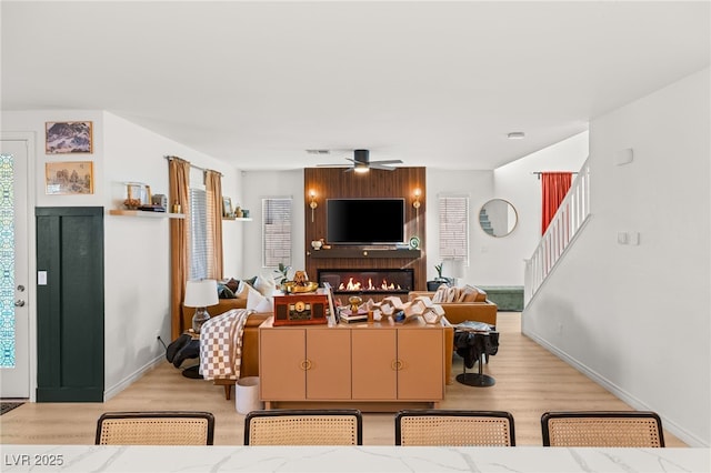 living room with a fireplace, light hardwood / wood-style floors, and ceiling fan