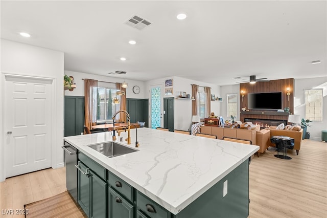 kitchen with a kitchen island with sink, sink, ceiling fan, and green cabinetry