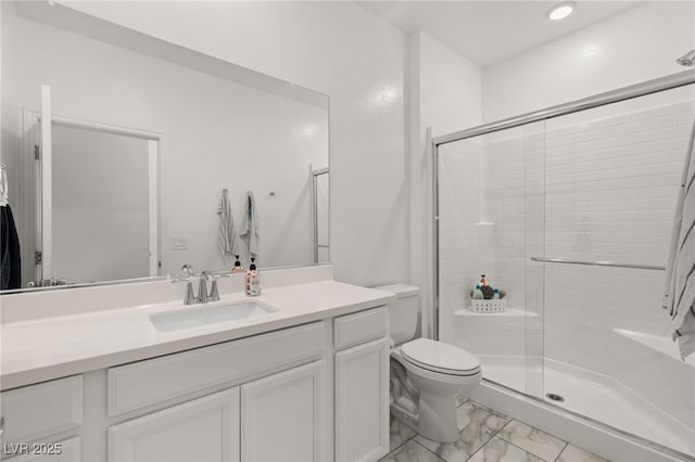 bathroom featuring vanity, toilet, and a shower with door