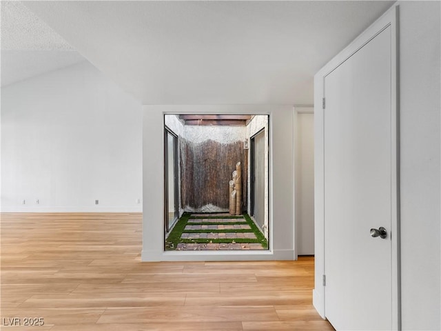 hall featuring vaulted ceiling and light hardwood / wood-style flooring