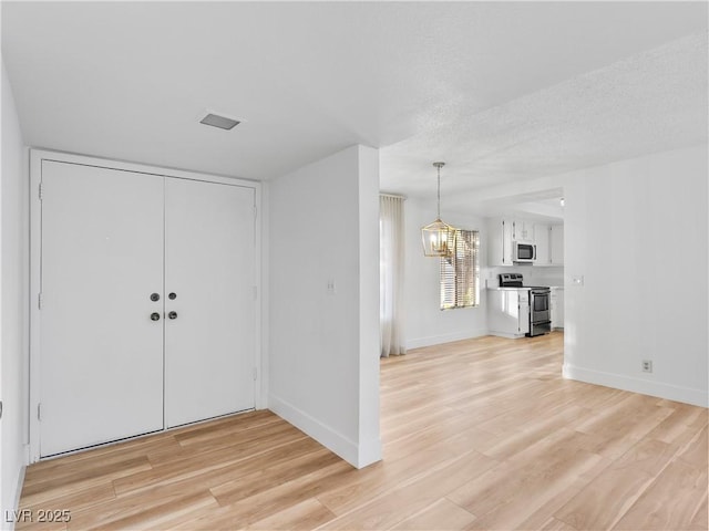 entrance foyer with an inviting chandelier, light hardwood / wood-style flooring, and a textured ceiling