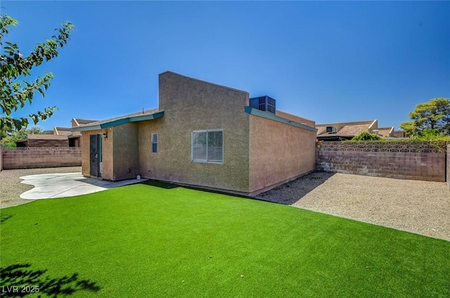 rear view of house featuring central AC unit, a yard, and a patio