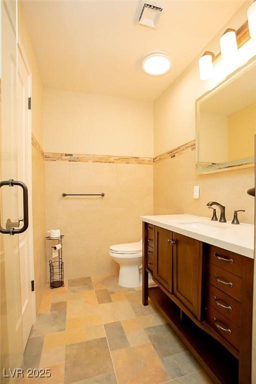 bathroom with tile walls, vanity, and toilet