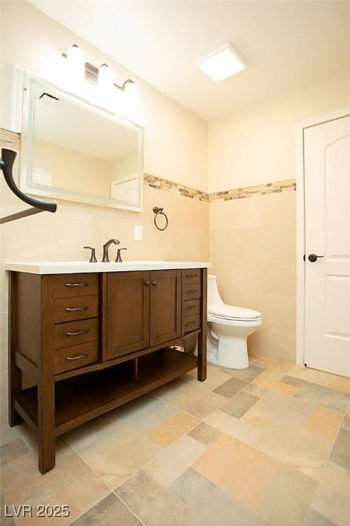 bathroom with vanity, tile walls, and toilet