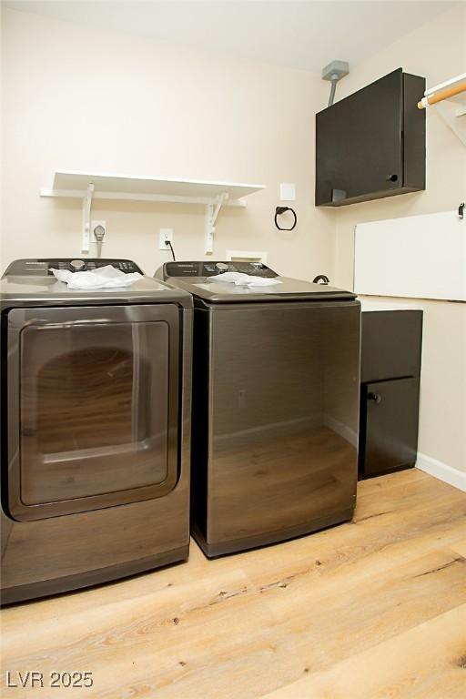 clothes washing area featuring washing machine and dryer and light hardwood / wood-style floors