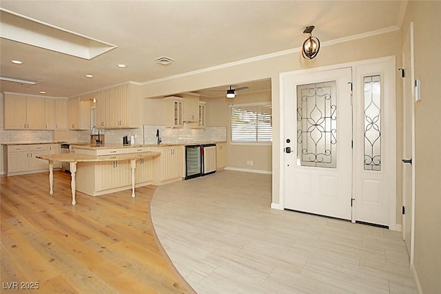 kitchen with ornamental molding, beverage cooler, a kitchen breakfast bar, and sink