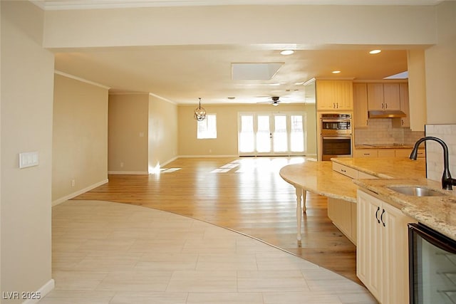 kitchen with light brown cabinetry, sink, beverage cooler, light stone counters, and french doors