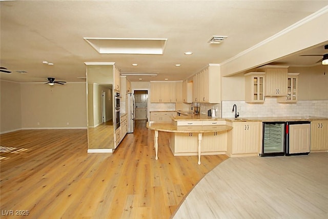 kitchen featuring sink, stainless steel fridge, a kitchen bar, and light hardwood / wood-style flooring