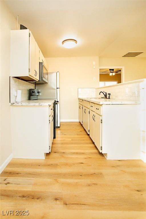 kitchen with sink, white cabinets, light hardwood / wood-style floors, and electric stove