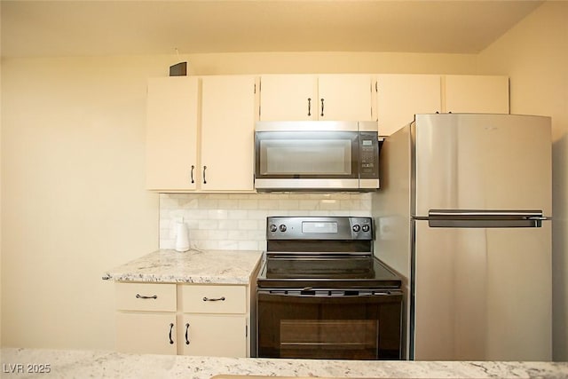 kitchen featuring light stone countertops, backsplash, stainless steel appliances, and white cabinets