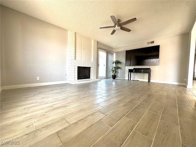 unfurnished living room featuring a fireplace, a textured ceiling, and ceiling fan