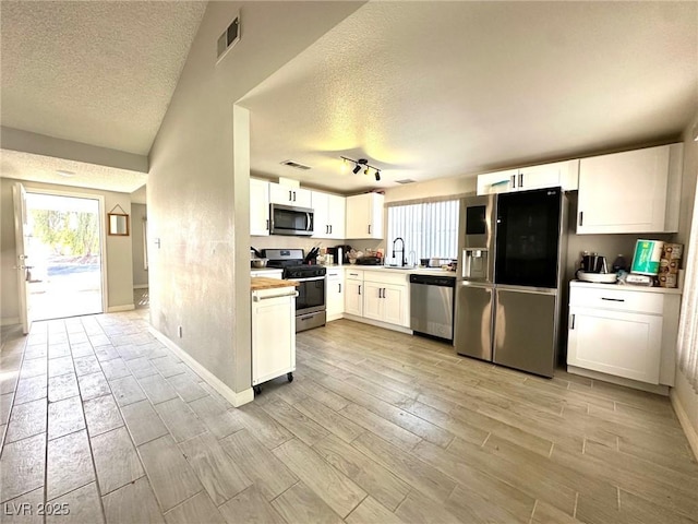 kitchen with white cabinets, sink, stainless steel appliances, and a textured ceiling