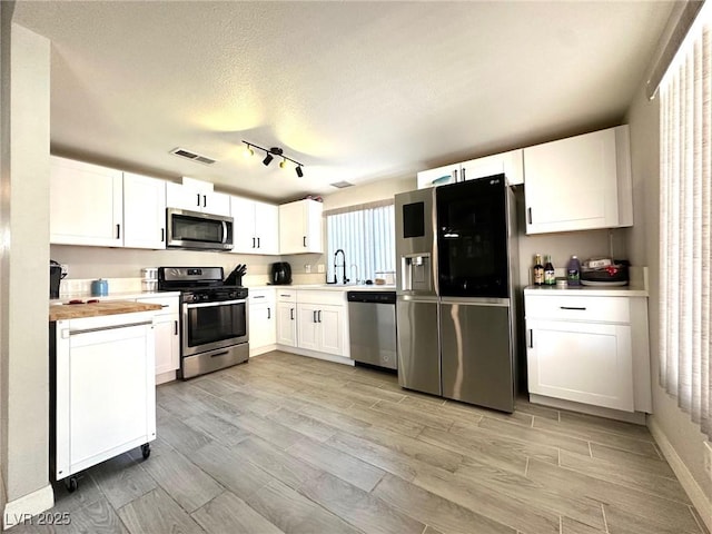 kitchen featuring white cabinets, sink, appliances with stainless steel finishes, and wooden counters