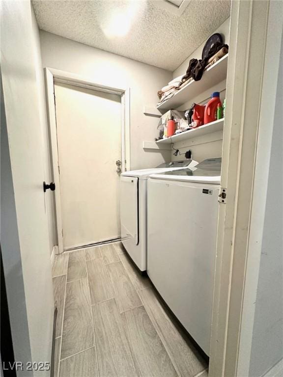 laundry area with a textured ceiling and washing machine and dryer