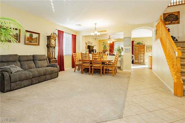 living room featuring light tile patterned floors and ceiling fan with notable chandelier