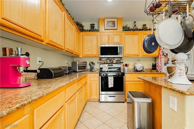 kitchen featuring light tile patterned flooring, light stone counters, stainless steel appliances, and light brown cabinets