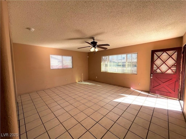 unfurnished room featuring light tile patterned floors, a textured ceiling, and ceiling fan