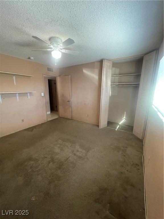 unfurnished bedroom with carpet flooring, a textured ceiling, and ceiling fan