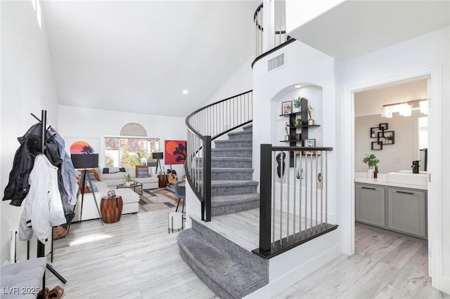 staircase featuring hardwood / wood-style floors, sink, and high vaulted ceiling