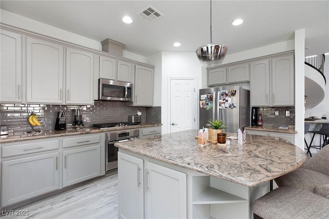 kitchen featuring decorative backsplash, pendant lighting, a center island, and stainless steel appliances