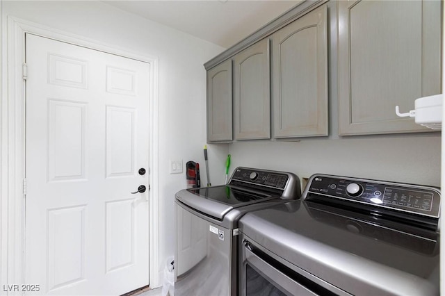 clothes washing area featuring washer and clothes dryer and cabinets