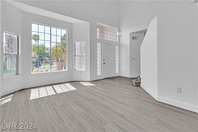 foyer entrance with a healthy amount of sunlight, an inviting chandelier, and light hardwood / wood-style flooring