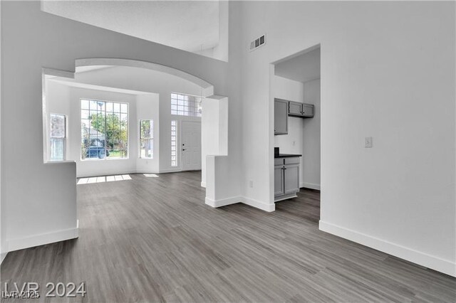 unfurnished living room featuring a towering ceiling and dark wood-type flooring