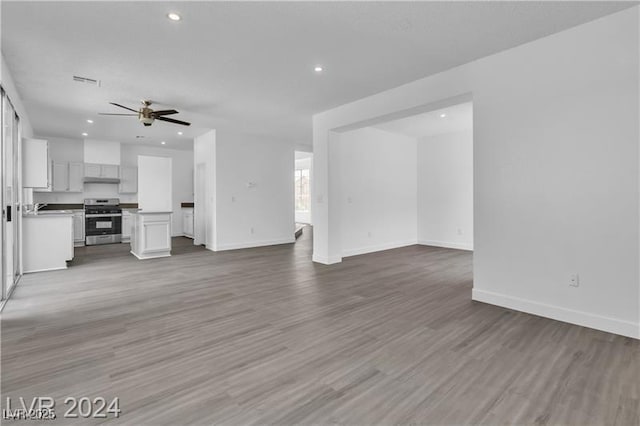 unfurnished living room featuring ceiling fan, sink, and light wood-type flooring