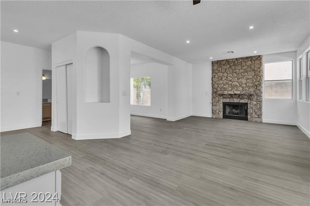 unfurnished living room with hardwood / wood-style flooring and a stone fireplace