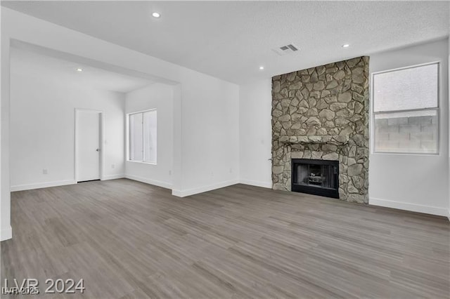 unfurnished living room featuring a fireplace, wood-type flooring, and a textured ceiling