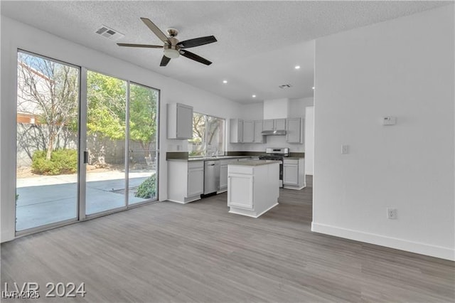 kitchen with a textured ceiling, stainless steel appliances, ceiling fan, and hardwood / wood-style flooring