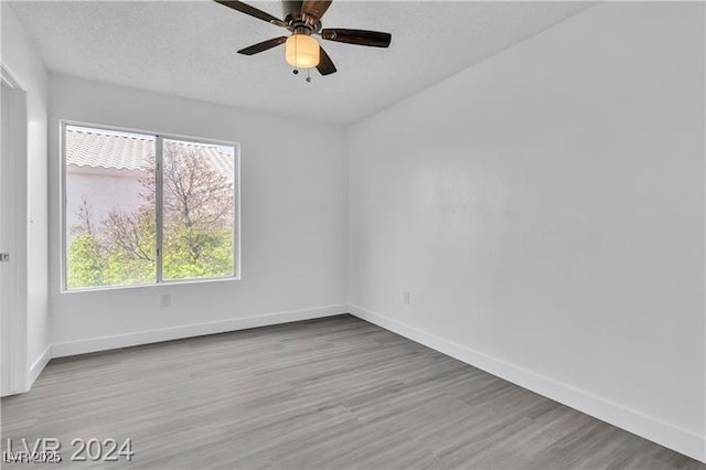 empty room with ceiling fan and light hardwood / wood-style flooring