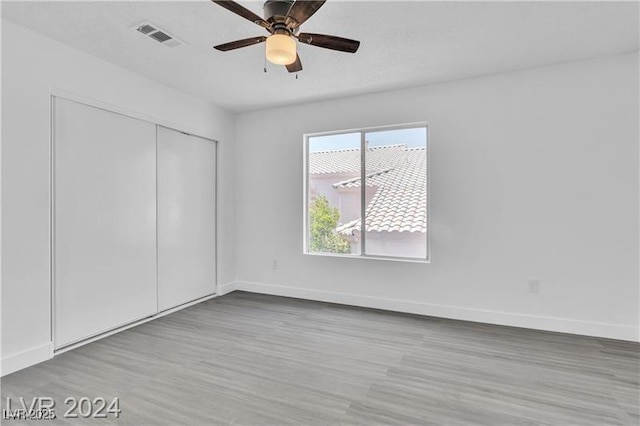 unfurnished bedroom with ceiling fan, light hardwood / wood-style floors, and a closet