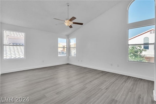 spare room with light wood-type flooring, high vaulted ceiling, and ceiling fan