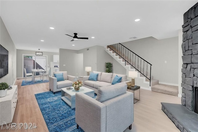 living room with ceiling fan, light wood-type flooring, and a fireplace