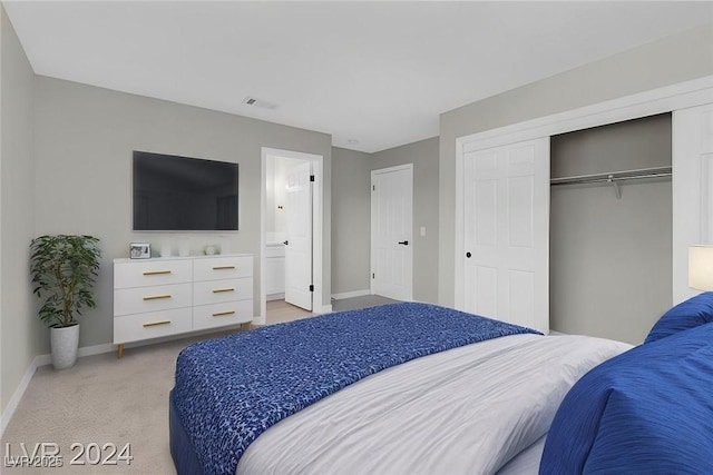 bedroom with ensuite bath, light carpet, and a closet