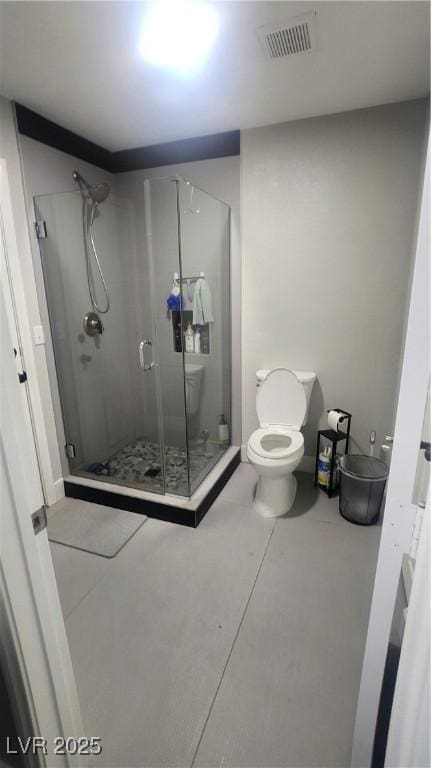 bathroom featuring a shower with door and toilet