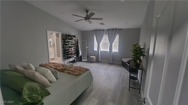 bedroom with vaulted ceiling, ceiling fan, light wood-type flooring, and ensuite bath